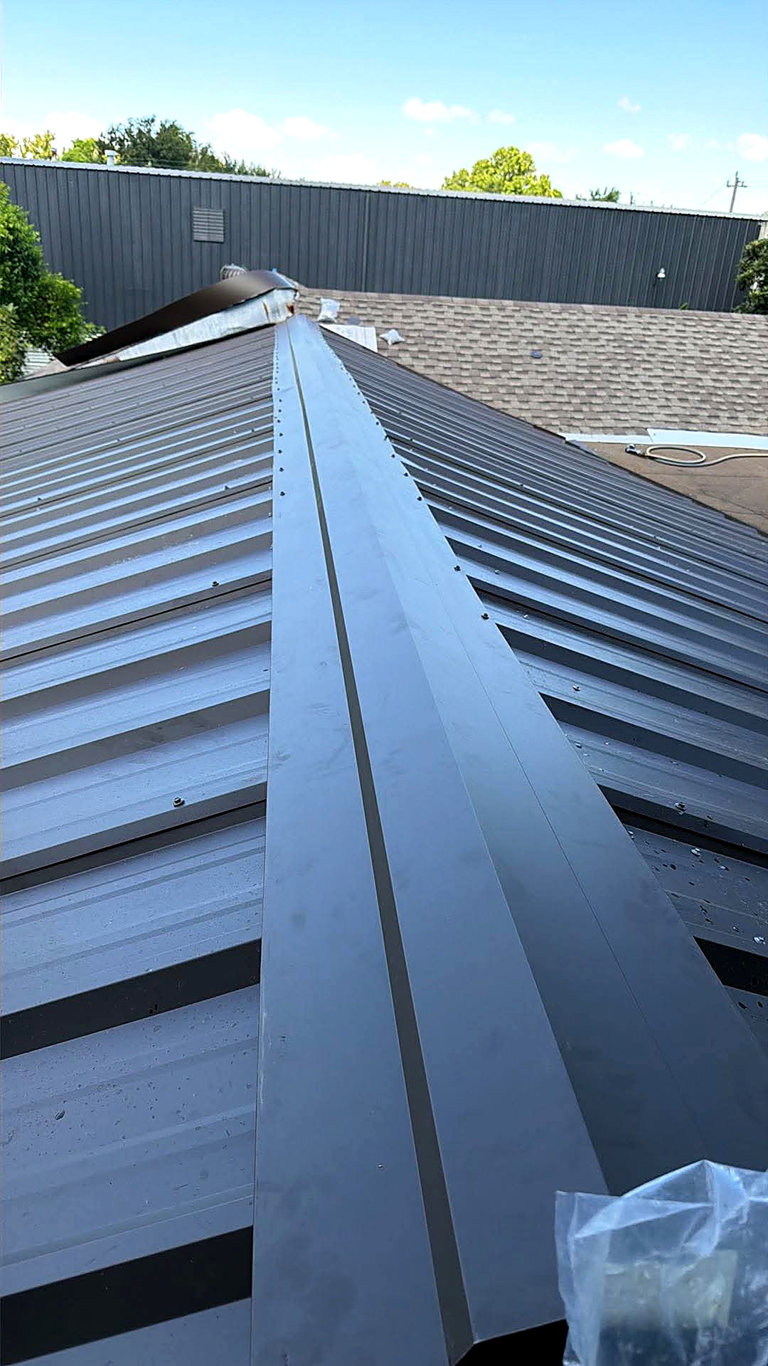 Newly installed standing seam steel roof under a clear Texas sky